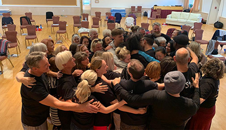 Large group of people hugging in a circle after healing session.